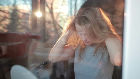 Through the window portrait of girl enjoying her hair
