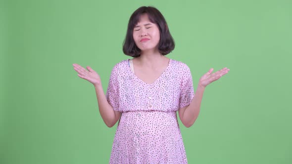 Confused Asian Pregnant Woman Shrugging Shoulders