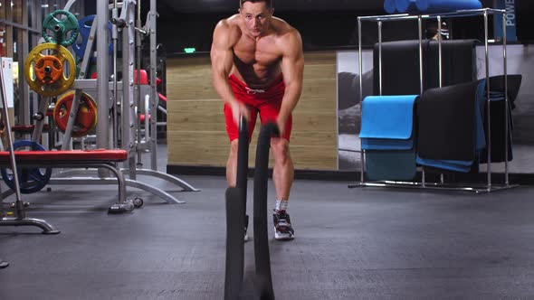 Adult Fit Man Training His Hands with an Exercise with Ropes