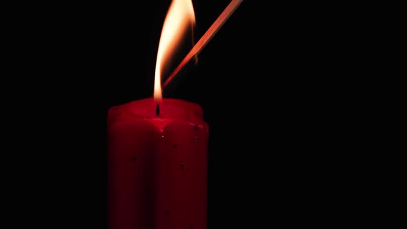 The Fire Of A Match Lights A Red Christmas Candle.