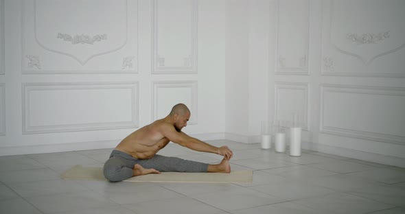 Muscular Male Yogi Doing Leg Stretching. He Sprains His Left Leg