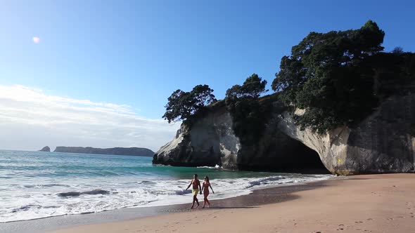 Couple walking along beach, Te Whanganui-A-Hei (Cathedral Cove), New Zealand