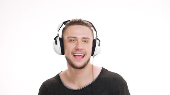 Portrait of Young Handsome Man Listening Music in Headphones and Dancing