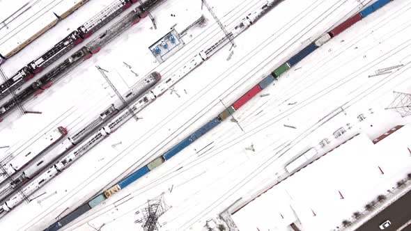 Freight Train with Colored Cars in Winter Goes Through the Railway Station