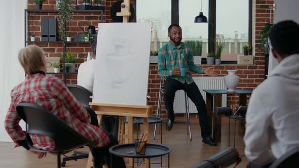 Young Man Teaching Creative People to Draw on Canvas