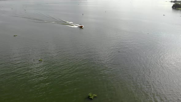 Aerial view of wakeboarding on river at sunset. Friends on boat having fun, doing water extreme spor