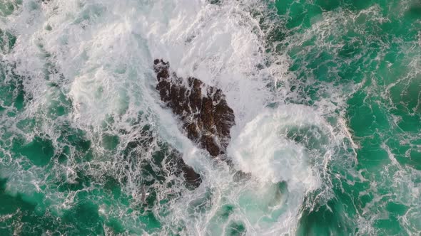 Aerial Slow Motion Shot of Seagull Flies Over Turquoise Sea Wave Breaks on the Stones