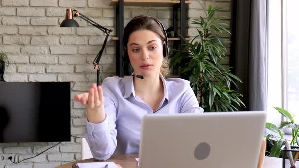 Young call operator businesswoman wears headset customer service manager looking and speaking to web