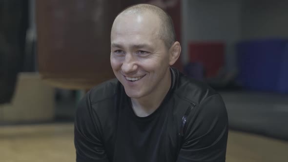 Close-up Portrait of Cheerful Adult Caucasian Sportsman Talking To Someone in Gym. Joyful Man with