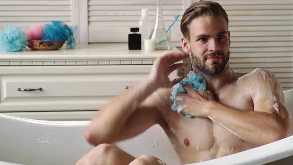 Sexy Young Man Washing in Bathrobe in Bathroom. Hygiene and Spa. Sexy Sport Muscle Strongface Guy