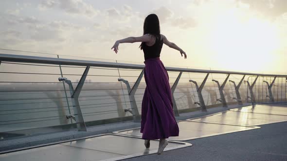 Elegant Caucasian Ballerina Spinning on Tiptoes on Bridge in the Morning. Wide Shot Portrait of