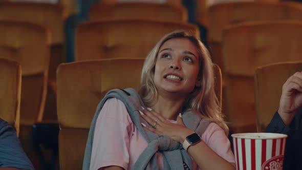 Attractive cheerful young caucasian woman watching horror movie in cinema theate.