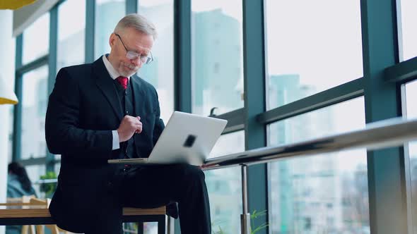 Grey-haired businessman working on a laptop. 