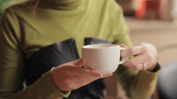 Young Woman Drinks Tea in a Cafe