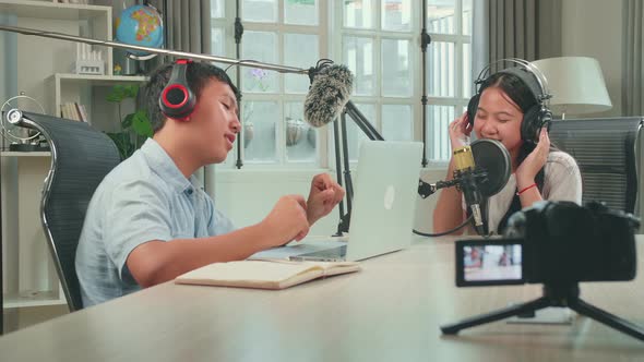 Camera Recording Of Asian Kid Girl Singing While Recording Podcast With Boy Host In Studio