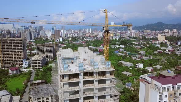 Construction crane on construction site against backdrop of mountains and city.