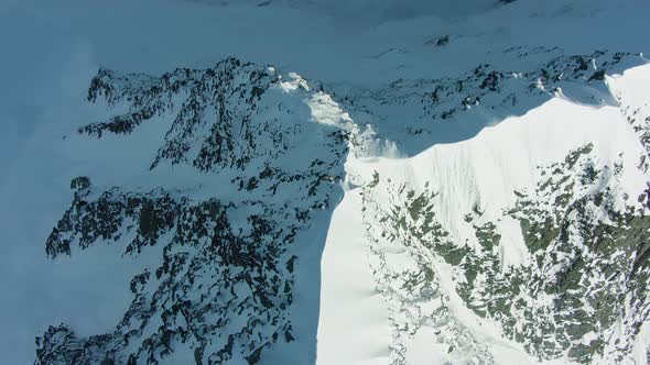 Snowy Top and Ridge of Mountain in European Alps in Sunny Day. Aerial View