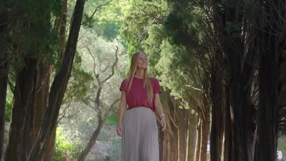 A Young Woman Tourist Walks Along the Valley in the Park Milocer Near the City of Budva