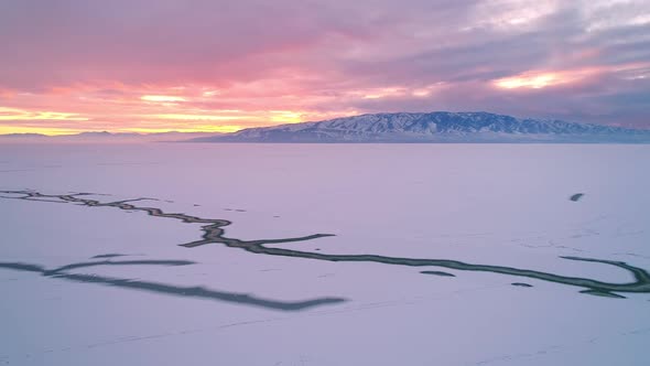 Colorful winter sunset over Utah Lake frozen in winter