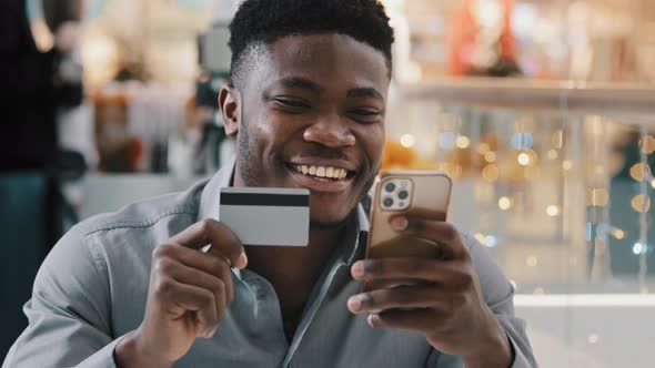 Satisfied African American Man Makes Purchase in Online Store Pays for Goods with Credit Card on