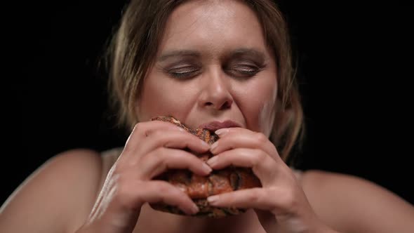 Closeup Front View Hungry Obese Woman Eating Delicious Unhealthy Bun at Black Background