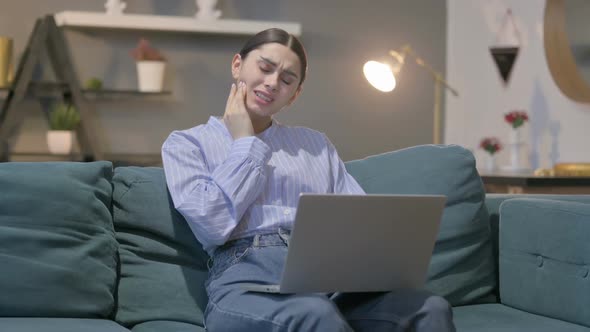 Hispanic Woman with Laptop having Toothache on Sofa