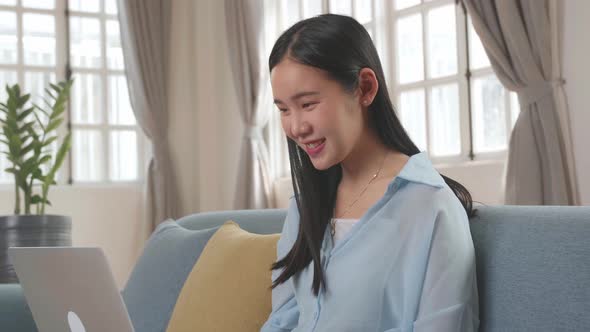 Female Using Laptop And Smiling In Living Room