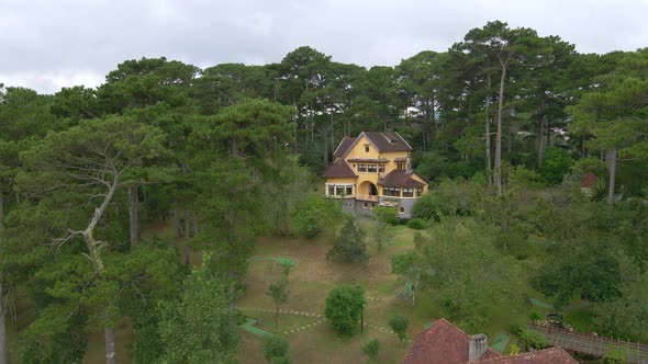 Aerial drone flying around a villa with French colonial style between pine trees forest_Dalat Vietna