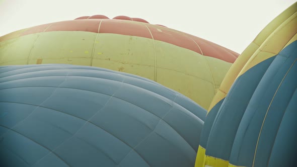 Tops of Huge Colorful Air Balloons Filling with Hot Air