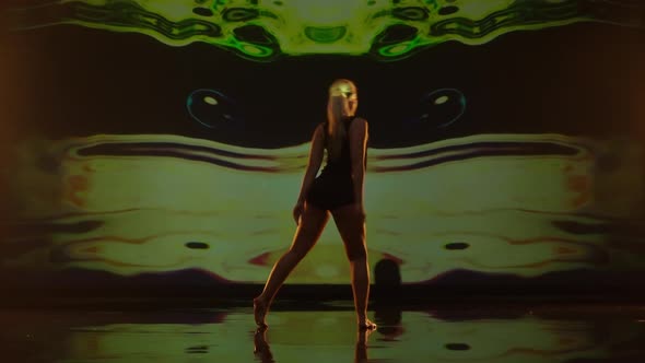 Artistic Young Woman Dancing Against Dark Animated Background on Studios Stage