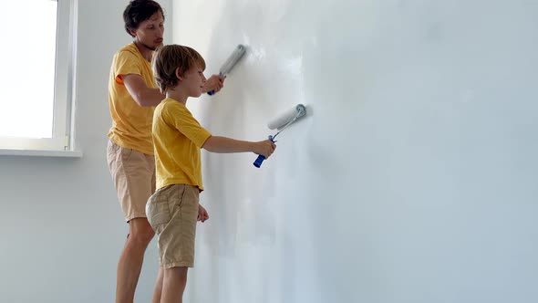 A Father and Son Both Wearing a Yellow Tshirt Paint the Wall Using a Roller Painter