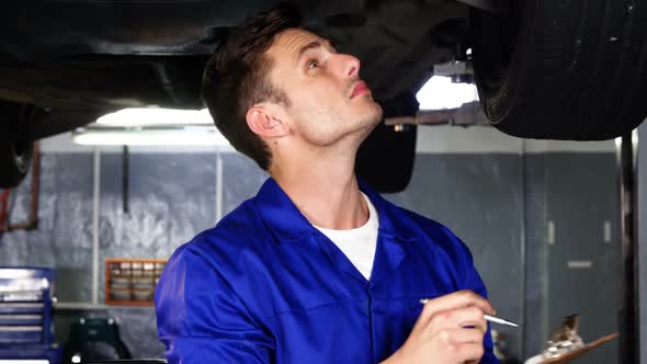 Mechanic writing on clipboard in repair shop