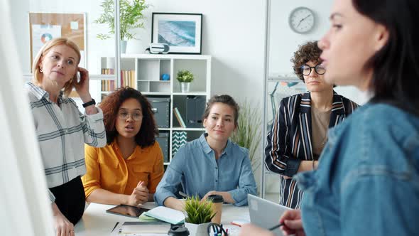 Businesswoman Making Presentation Giving Good News To Employees Talking Indoors in Office