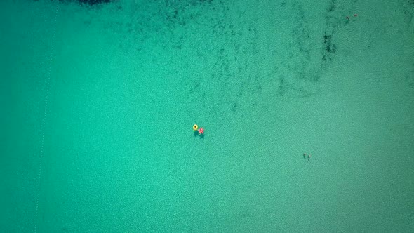 Aerial abstract view of two people floating in open sea on inflatables.