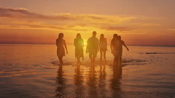 Big happy family or group of five friends is having fun against sunset beach. Beach holidays concept