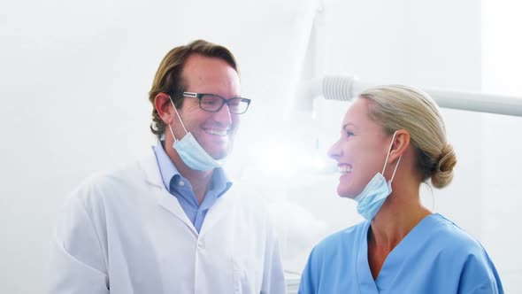 Smiling dentist talking to dental assistant