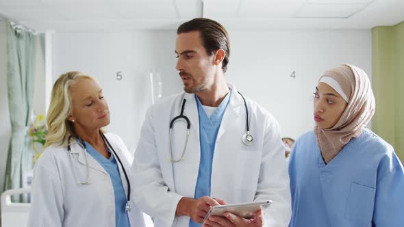 Three doctors using tablet computer in hospital ward 4k