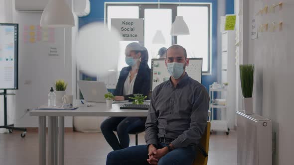 Portrait of Businessman Sitting at Office Desk Wearing Medical Face Mask