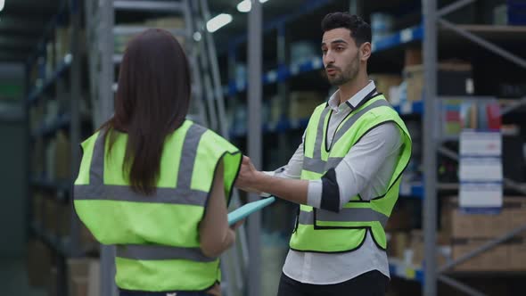 Professional Warehouse Manager Talking with Freight Agent Gesturing Standing in Industrial Storage