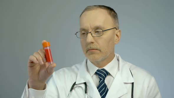 Doctor Looking at Vial With Donated Blood Sample for Analysis, HIV Awareness