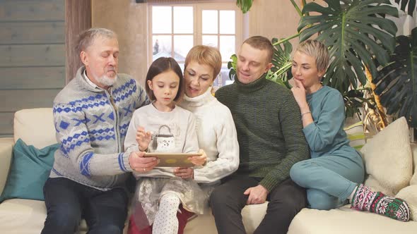 Friendly Extended Family Watching Photos From Tablet