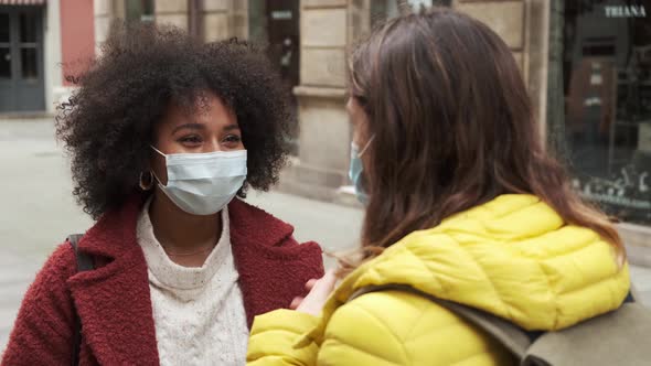 Multiethnic women in masks talking to each other on street