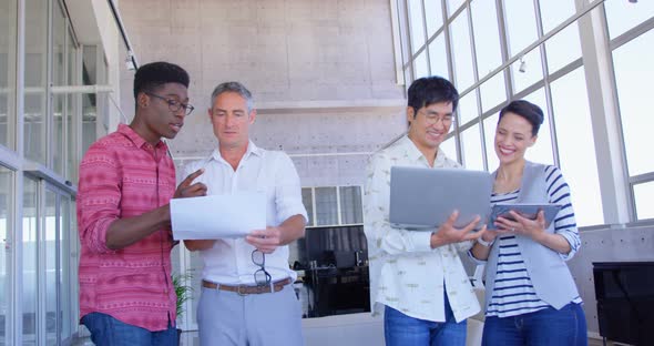 Multi-ethnic business people discussing over document and laptop in modern office 4k