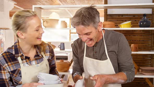 Male and female potters holding pottery in workshop