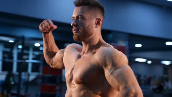 Circle view on bodybuilder without shirt in gym. Man with strong hands and big muscles.
