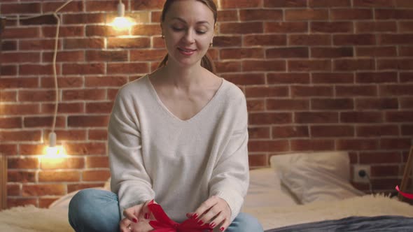 Caucasian Woman is Packing Gift While Sitting on Bed