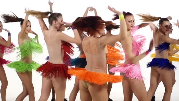 Pretty Girls Dancing Synchronously in Colorful Dresses Over White Background. Slow Motion