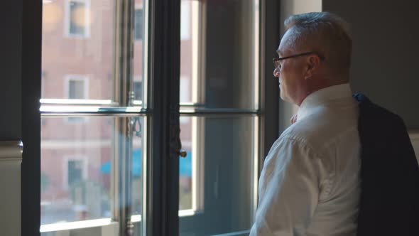 Concentrated Thoughtful Senior Businessman Looking Away at Office Window