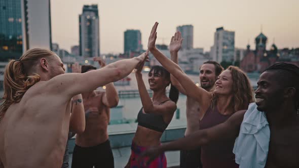 Multiracial Group of Athletes Men and Women in Sports Uniforms Doing a High Five After Completing a