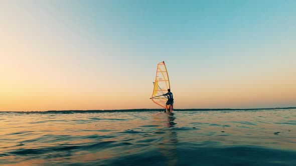 Sunset Lake with a Group of People Floating on Sailboard